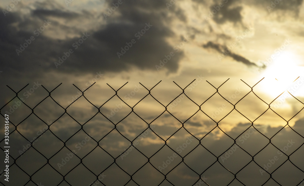 Restricted area concept. A metal mesh fence enclosing a restricted area (quarantine, prison, production area) Restricted area concept. A metal mesh fence enclosing a restricted area (quarantine, prison, production area)