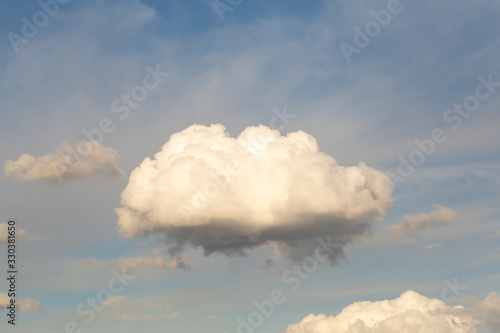 A cumulus cloud floating across the sky. Little cumulus before the rain in the rays of the setting soft sun photo