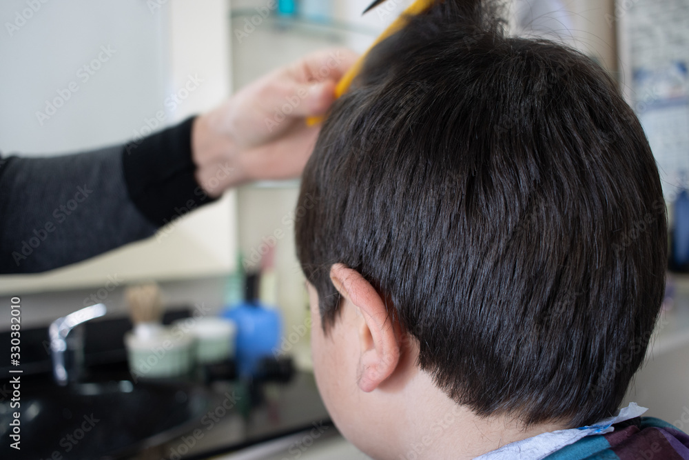 Fototapeta premium Cheerful Caucasian boy getting hairstyle in barbershop.
