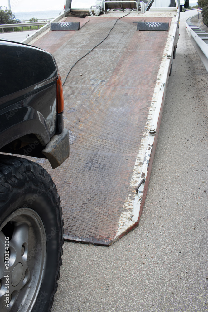 Loading broken car on a tow truck on a roadside