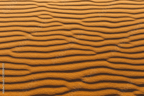 Orange texture of sand dune. Abstract shape, background, shadow and sun light. Sahara desert.