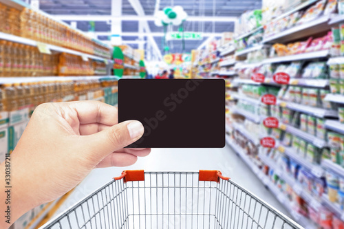 Hand holding credit card with supermarket background