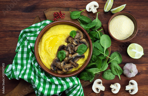 Corn porridge (polenta) with mushrooms on a brown wooden board. Healthy homemade food