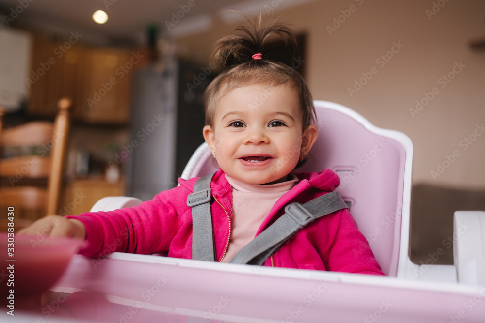 Little cute baby girl are eating in hight chair. Portrait of little smiled child at home Little cute baby girl are eating in hight chair. Portrait of little smiled child at home