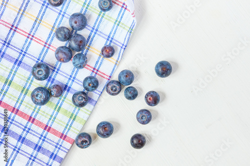 Blueberries scattered on a rag on a white wooden background. Top view.