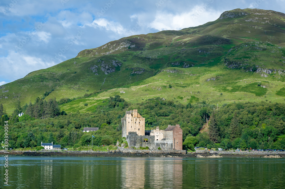 Sun beams at scottish highlands and Eilean Donan Castle view from the water. Hebrides landmarks, Scotland.