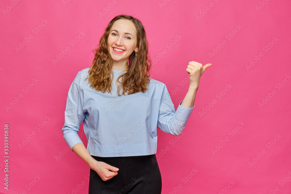 Stylish caucasian girl in a pale blue t-shirt pointing finger to abstract object on a pink background. Copy space. Stylish caucasian girl in a pale blue t-shirt pointing finger to abstract object on a pink background. Copy space.