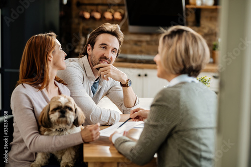 Young couple with a dog having a meeting with financial advisor at home.