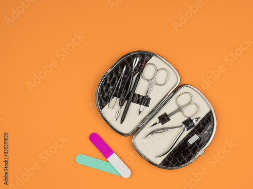 Kit accessories for manicure on orange background.