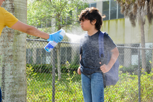 coronavirus kids school closed disinfect spray young boy head toe eyes closed holding bookbag covid19 disinfect spray shirt head toe eyes closed holding bookbag covid19