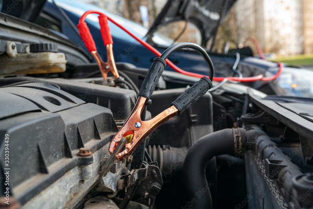 Fototapeta premium Jump cables on car low power battery. Broken car start attempt. Selective focus.