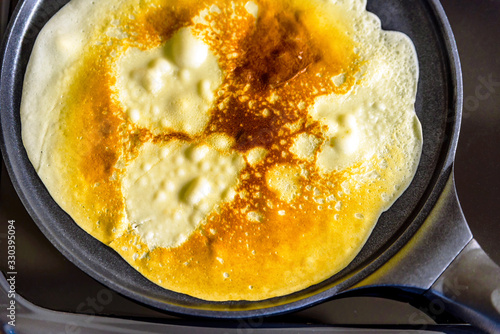 pancake frying pan with crepe pancake cooking on cooker in kitchen