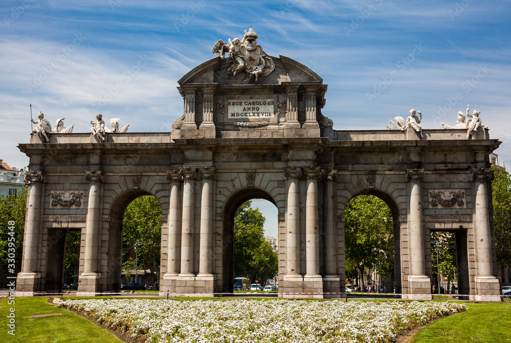 The famous Puerta de Alcala on a beautiful sunny day in Madrid City. Inscription on the pediment: Rey Carlos III year 1778