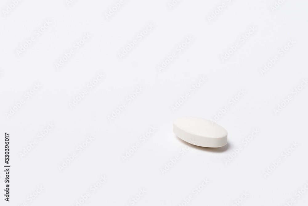 One white tablet oval shaped on a white background One white tablet oval shaped on a white background