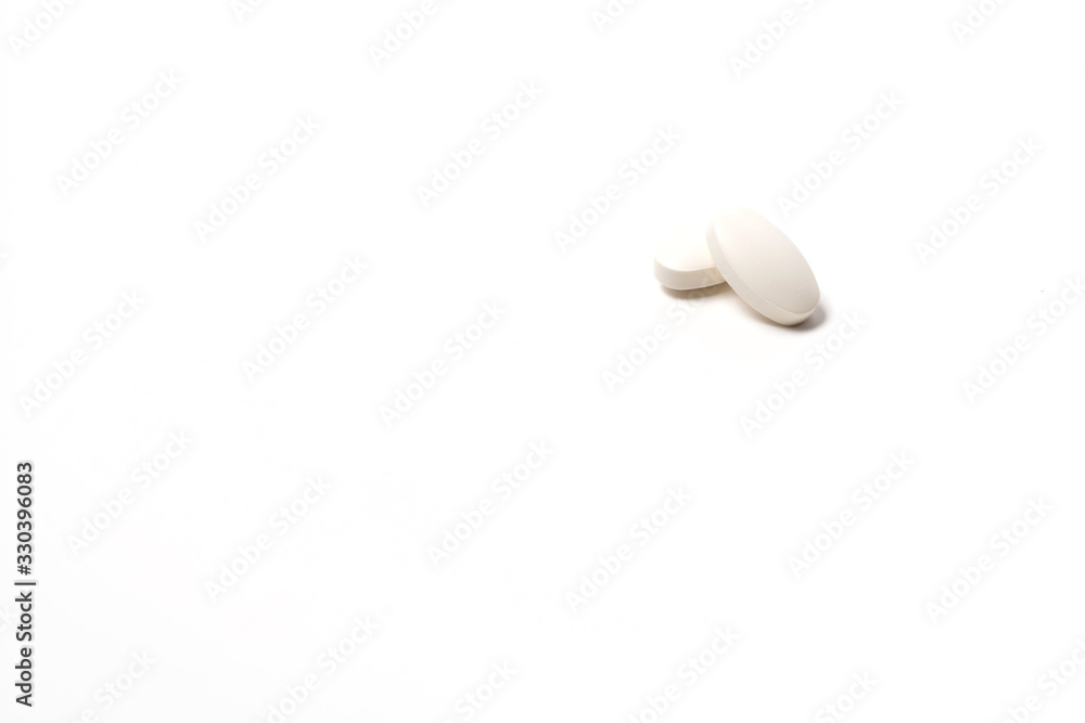 Two white tablet oval shaped on a white background. One lies on the other on top. Isolated Two white tablet oval shaped on a white background. One lies on the other on top. Isolated
