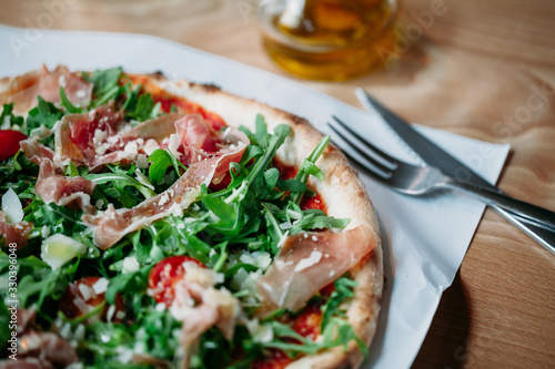 Italian pizza with prosciutto rocket and parmesan on wooden table