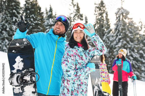 Happy couple with equipment at ski resort. Winter vacation