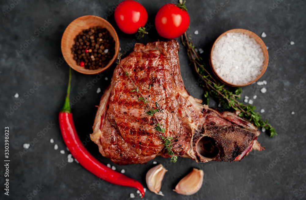 Grilled beef steak with spices on a stone background Grilled beef steak with spices on a stone background