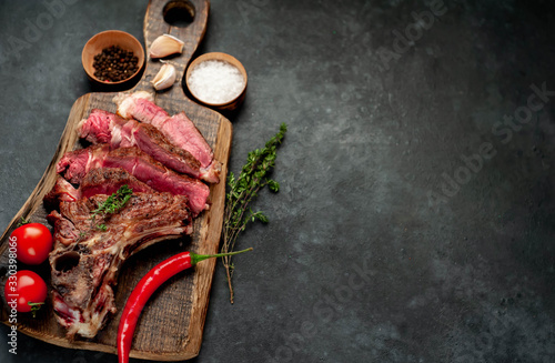 Grilled beef steak with spices on a cutting board on a stone background with copy space for your text