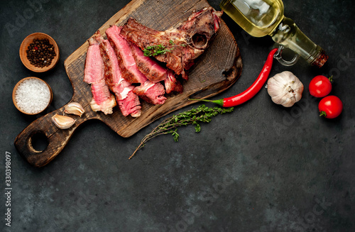 Grilled beef steak with spices on a cutting board on a stone background with copy space for your text