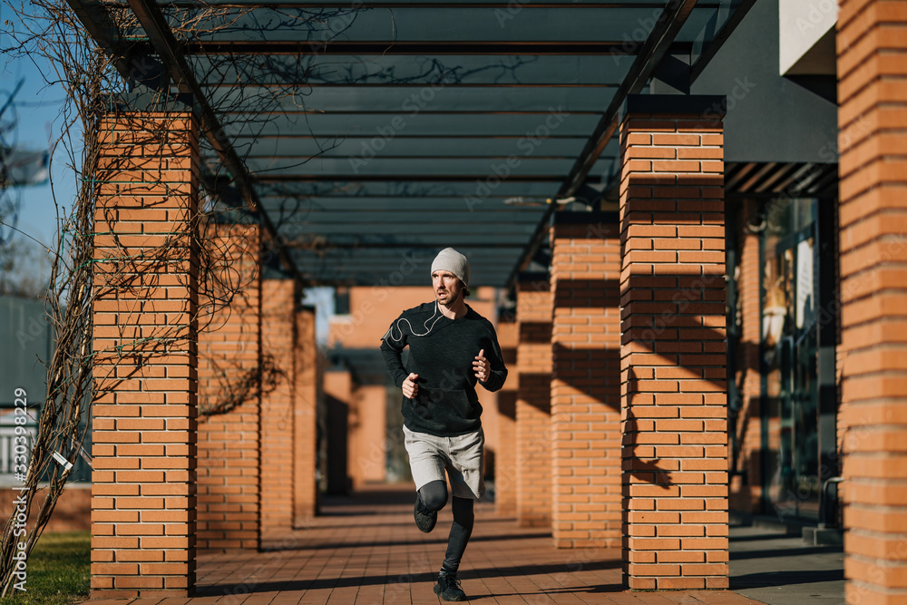 Full length of young athletic man running in the city. Full length of young athletic man running in the city.