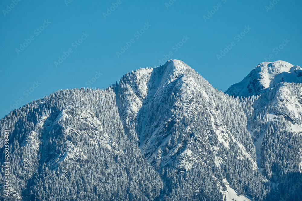 Obraz premium beautiful mountain range covered by the snow under the sun under clear blue sky