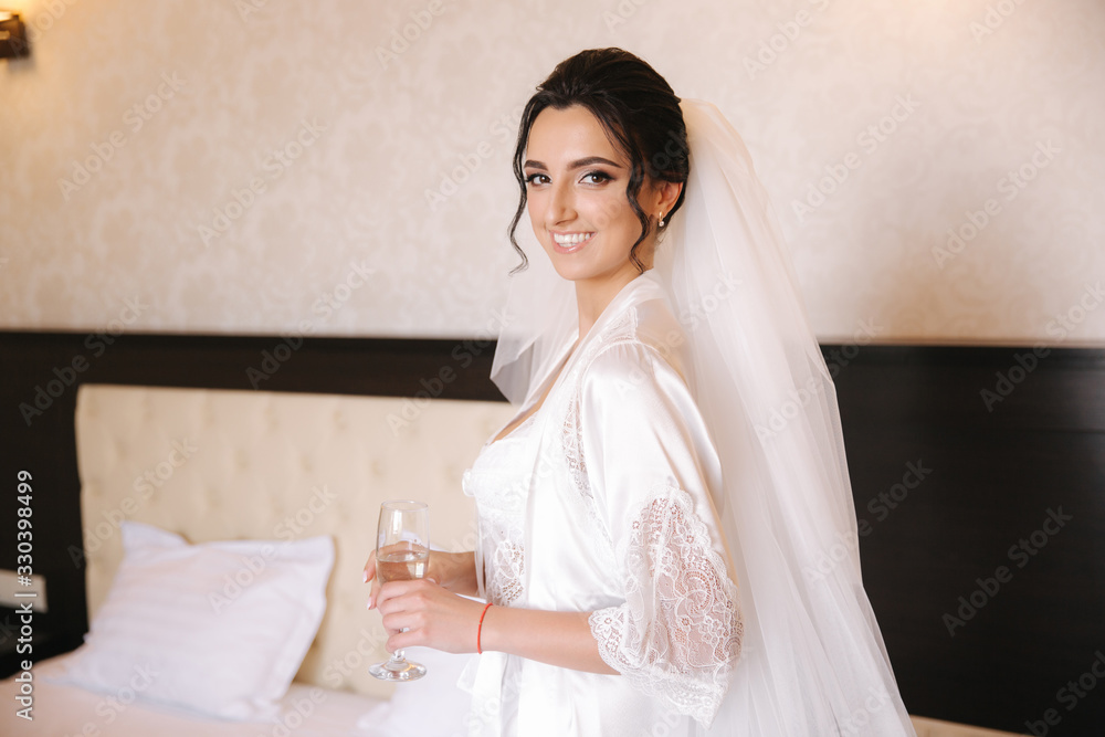 Portrait of gorgeous bride with glass of champagne at hotel in morning. Charming woman with great hairstyle and makeup Portrait of gorgeous bride with glass of champagne at hotel in morning. Charming woman with great hairstyle and makeup