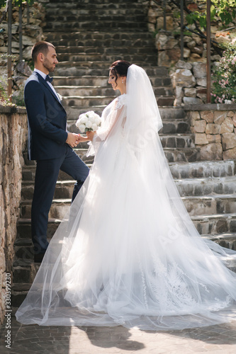 Beautiful bride with her handsome groom walking outside on theri wedding day. Happy newlyweds © Aleksandr