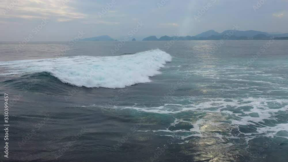 Long ocean wave in shape of pipe going to beach in 4K. surf white foam in clear turquoise blue water of Pacific off coast of Japan. reflection of sunset sky on surface of the sea. place for surfing Long ocean wave in shape of pipe going to beach in 4K. surf white foam in clear turquoise blue water of Pacific off coast of Japan. reflection of sunset sky on surface of the sea. place for surfing