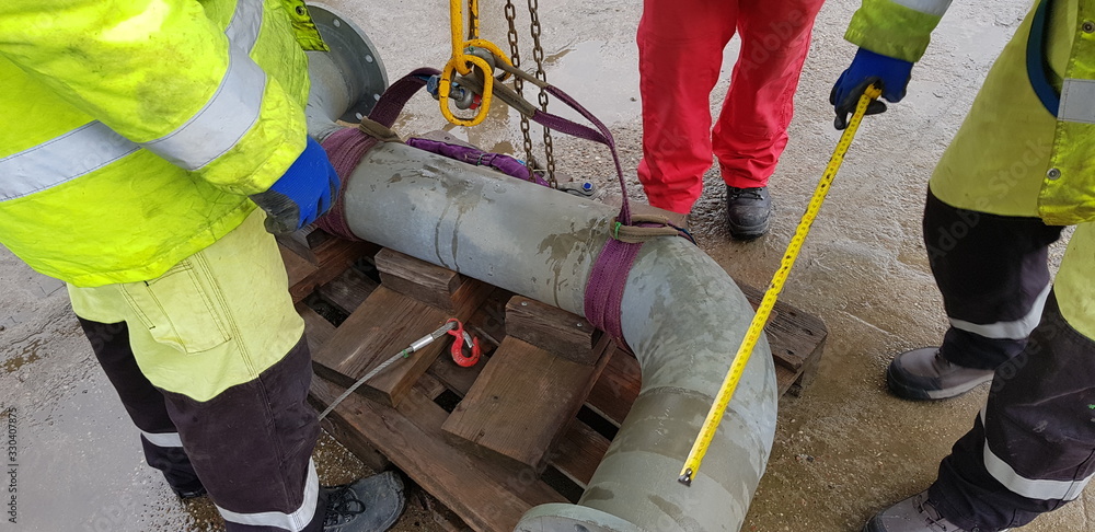 Fototapeta premium riggers move the pipe using two chain blocks