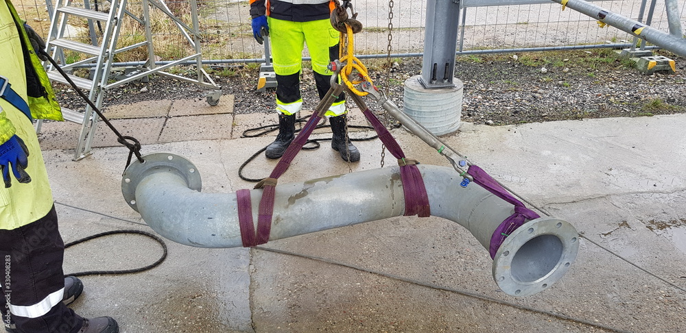 riggers move the pipe using two chain blocks