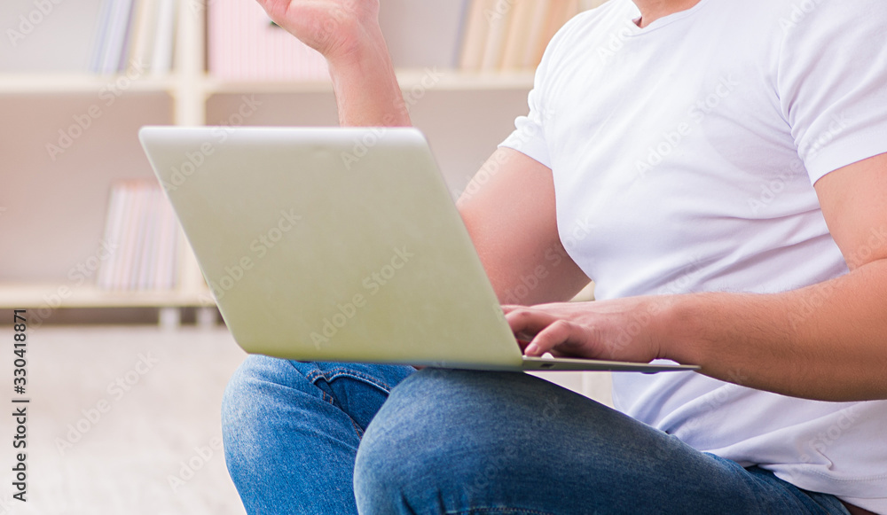 Naklejka premium Man working on laptop at home on carpet floor
