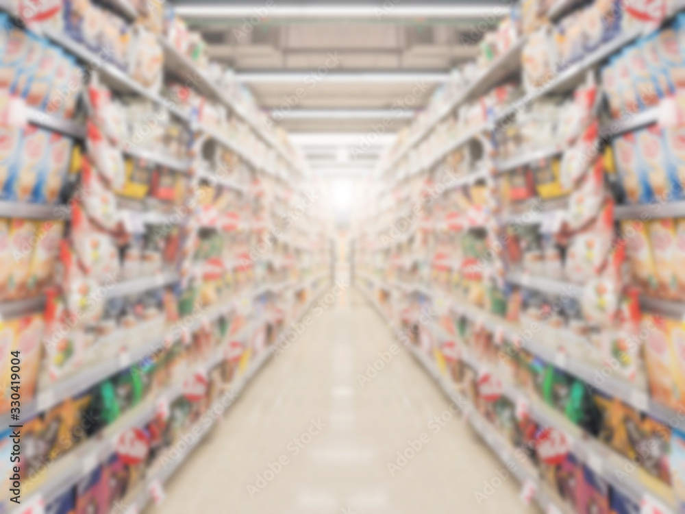 Supermarket aisle with product shelves abstract blur defocused background.
