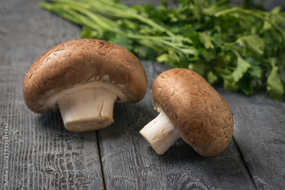 Parsley leaves and two king mushrooms on a wooden table. Vegetarian food. Parsley leaves and two king mushrooms on a wooden table. Vegetarian food.