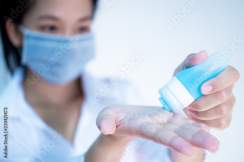 woman wearing hygienic protective mask using wash hand sanitizer alcohol standing on white background with copy space ,daily protection from corona virus or COVID-19 concept.