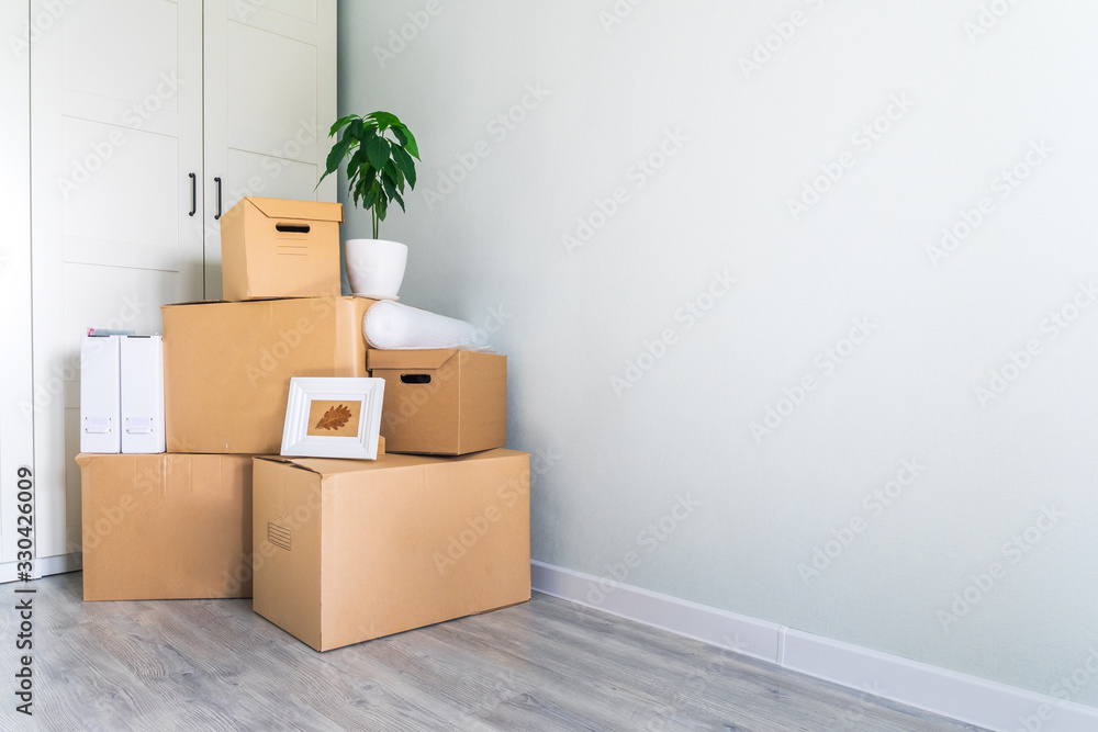 Fototapeta premium A lot of cardboard boxes with things to move. Check-in to a new apartment or office. Wall and closet in a new empty apartment. Copy space