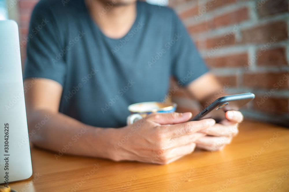 Business man hand use smartphone while drinking hot latte coffe in cafe