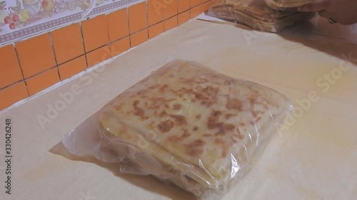 closeup of woman prepare  a fresh baked Moroccan square pancakes called Rghaif or Msemen in plastic bags to keep it in the refrigerator photo