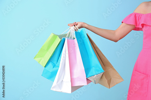 Beautiful young woman with shopping bags on color background