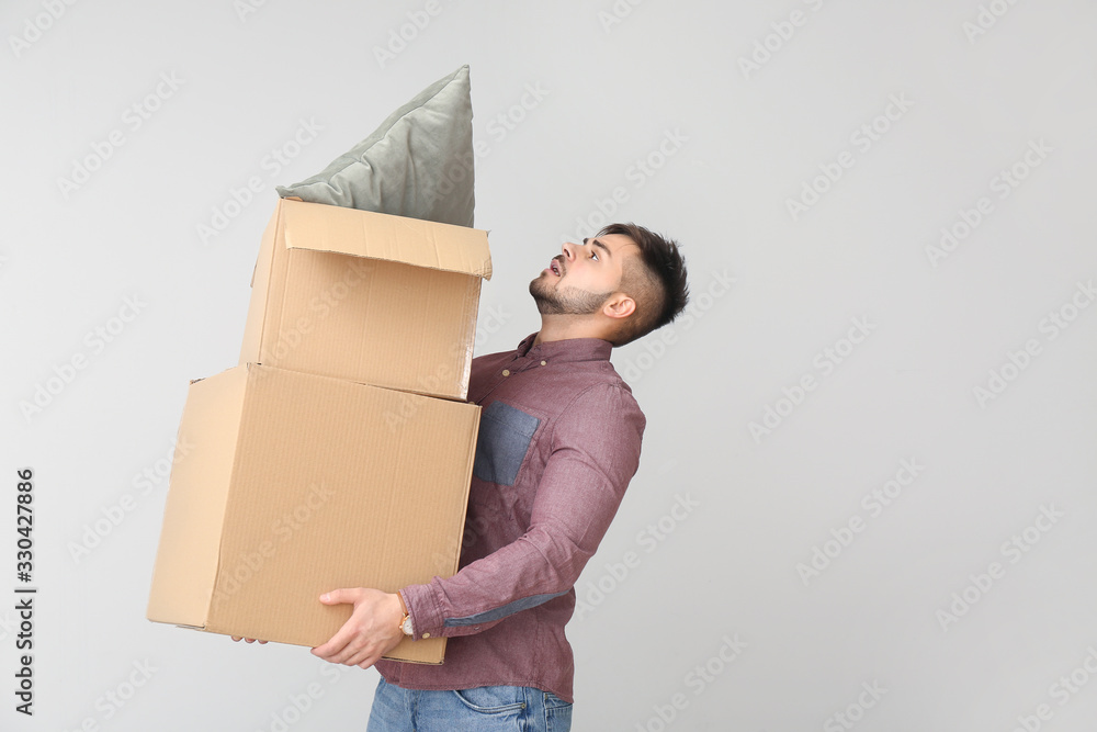 Troubled man with moving boxes on light background Troubled man with moving boxes on light background