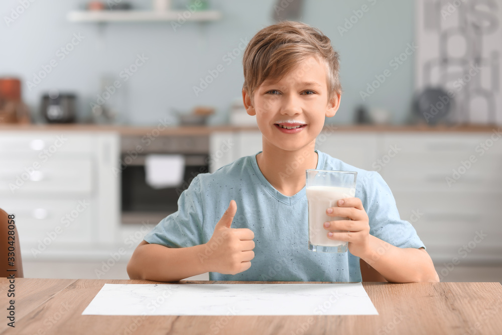 Little boy with milk showing thumb-up in kitchen Little boy with milk showing thumb-up in kitchen
