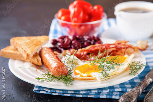 breakfast - egg, sausage, bacon and haricot in a plate on a table, selective focus, copy space