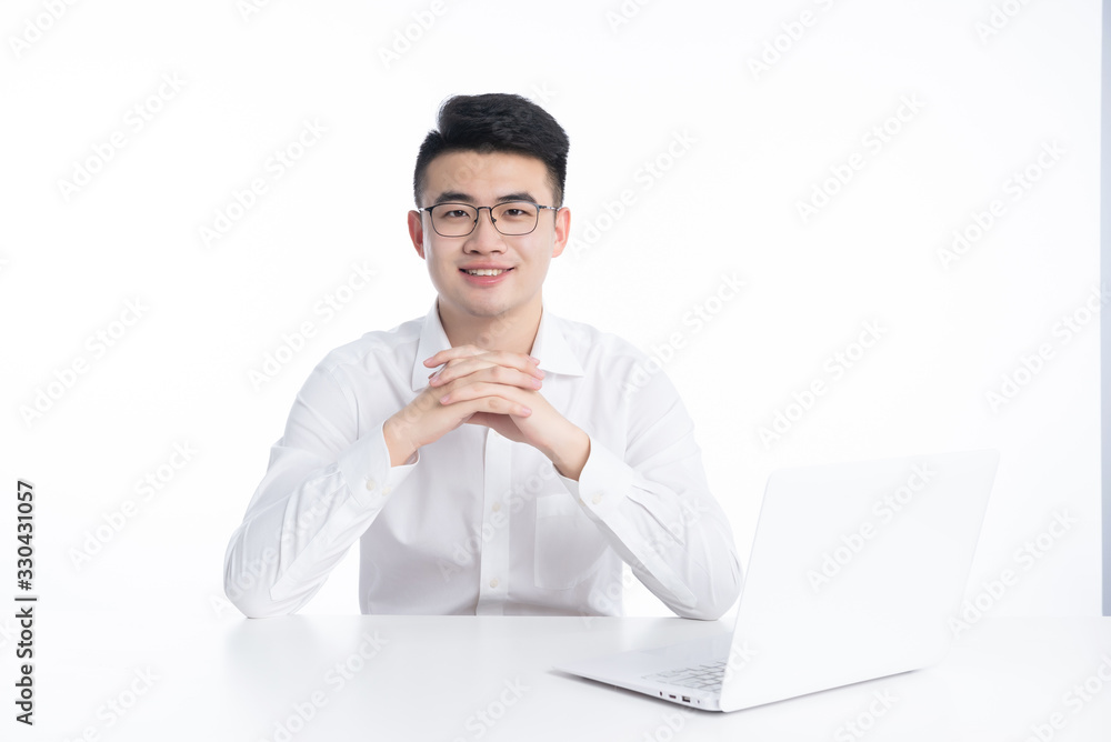 A young Asian man is using his mobile phone and laptop A young Asian man is using his mobile phone and laptop