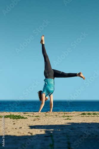 Young athletic woman doing balancing handstand exercise outdoor