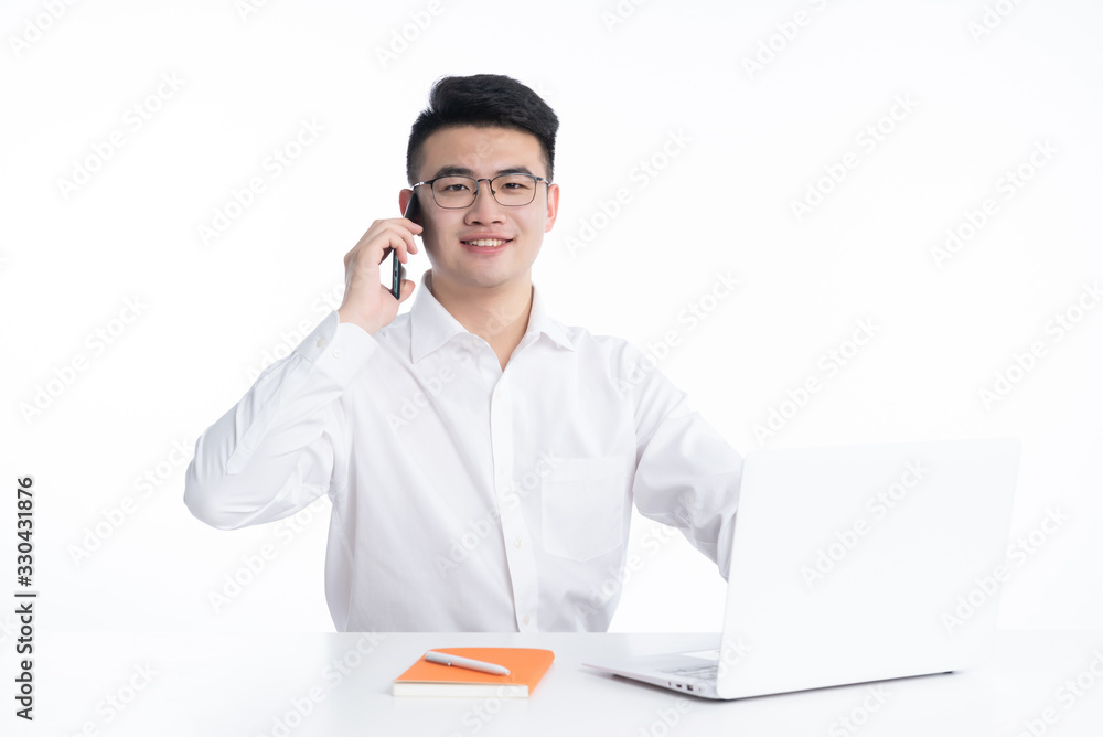 A young Asian man is using his mobile phone and laptop A young Asian man is using his mobile phone and laptop