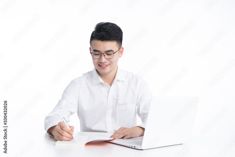A young Asian man is using his mobile phone and laptop A young Asian man is using his mobile phone and laptop