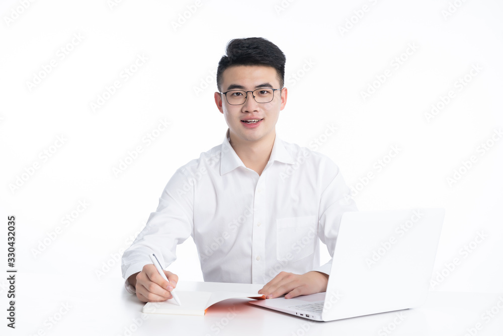 A young Asian man is using his mobile phone and laptop A young Asian man is using his mobile phone and laptop
