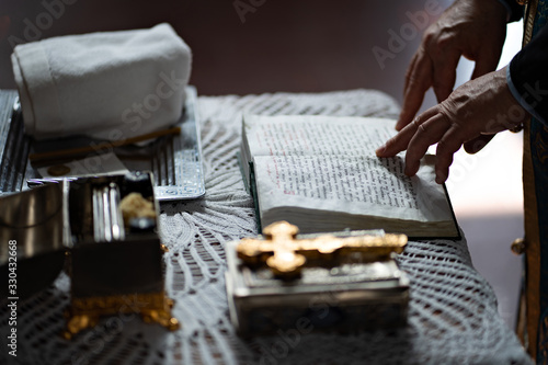 Orthodox priest reads prayer book at baptism