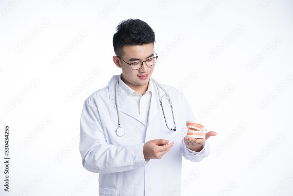An Asian male doctor works on a laptop
