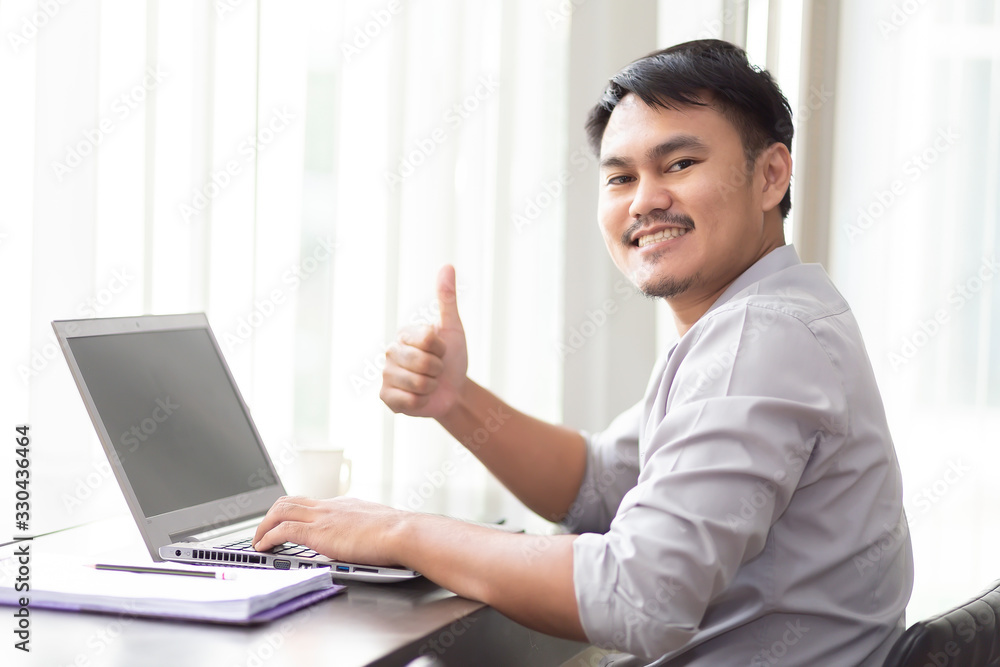 Asian businessmen are happy to work successfully with laptop and paper on the wooden table in the office building. Asian businessmen are happy to work successfully with laptop and paper on the wooden table in the office building.
